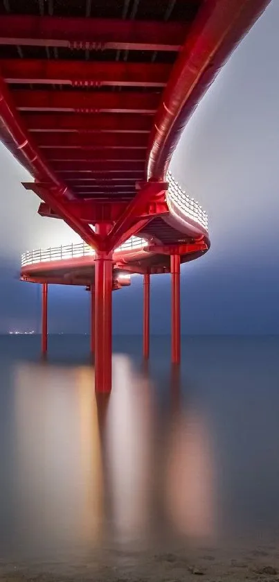 Dramatic red pier extending into a foggy ocean horizon with a calm reflection on water.