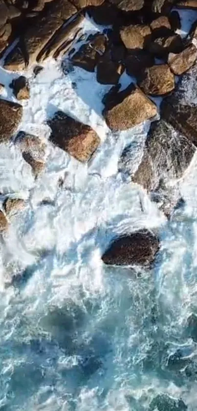 Aerial view of ocean waves crashing against rocks on the shore.