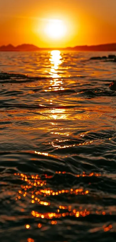 Vibrant sunset over ocean with orange reflections on rippling water.