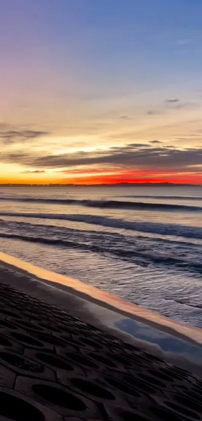 Sunset over ocean with vibrant colors and calming waves on the beach.