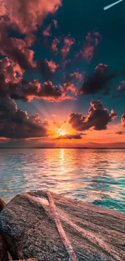 Stunning sunset over ocean with vibrant sky and rocks in foreground.