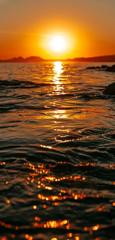 Tranquil ocean sunset with warm orange hues reflecting on water.