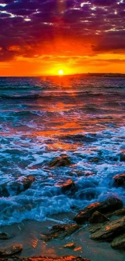 Vibrant seaside sunset wallpaper with waves and rocks.