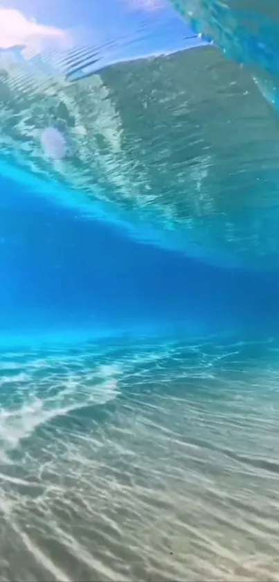 Underwater view of ocean waves with sunlight filtering through clear blue waters.