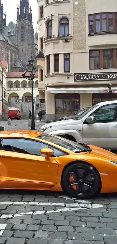 Orange sports car on city cobblestone street with historic buildings.