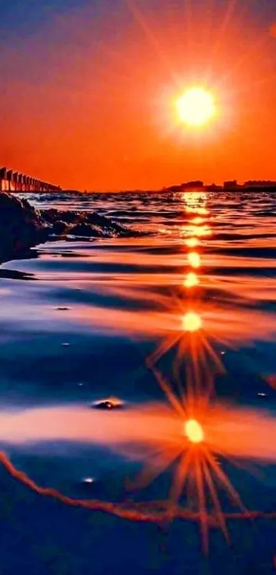 Orange sunset over ocean with vibrant reflection on water.