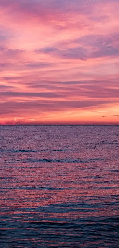 Pink ocean sunset over calm water with vibrant sky.