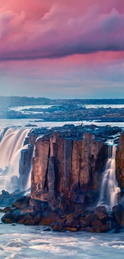 Waterfall against a vibrant pink sky at sunset.