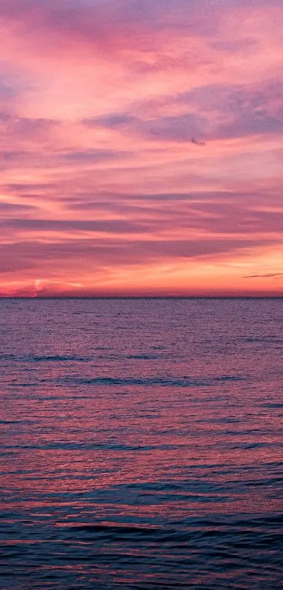 Vivid pink sunset over calm ocean waves, natural beauty wallpaper.