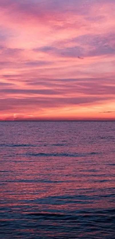 Pink sunset over a calm ocean with vibrant clouds.