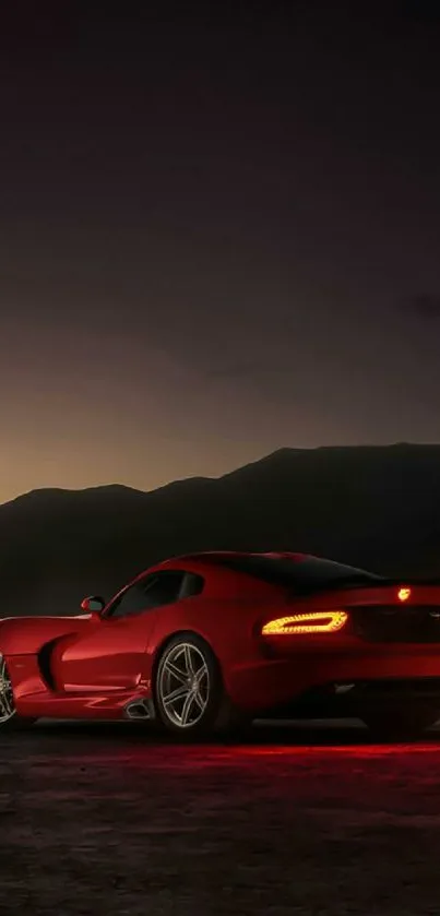 Red sports car at night with mountains.