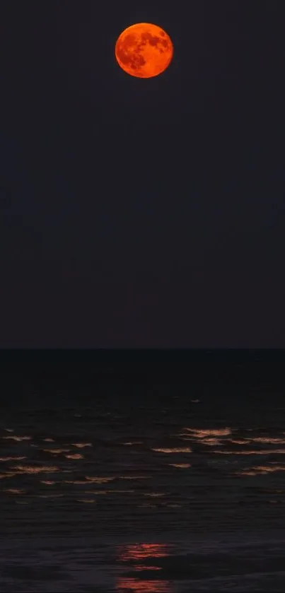 Red moon shining over a tranquil dark ocean at night.