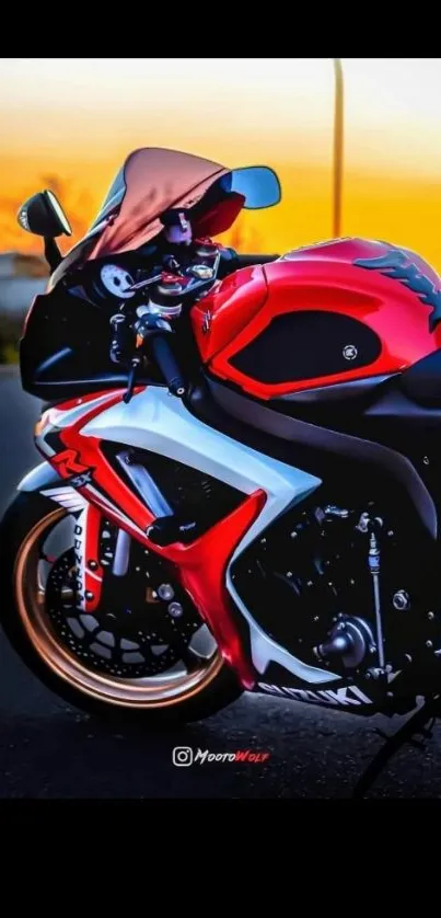 Red motorcycle against a vibrant orange sunset sky.