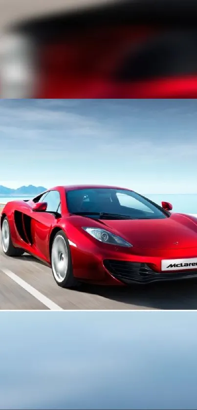 Red sports car on open road with blue sky background.