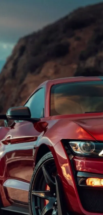 Sleek red sports car with mountain backdrop.