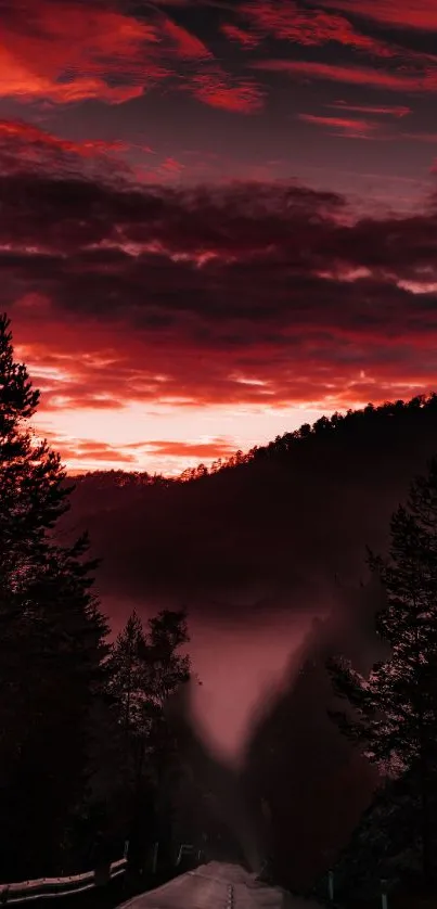 Dramatic red sunset over misty mountains and forest.