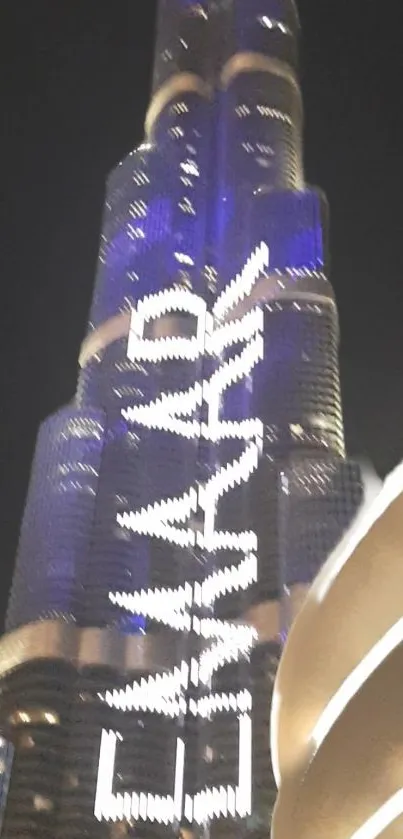 Skyscraper at night illuminated with blue lights and a striking city backdrop.