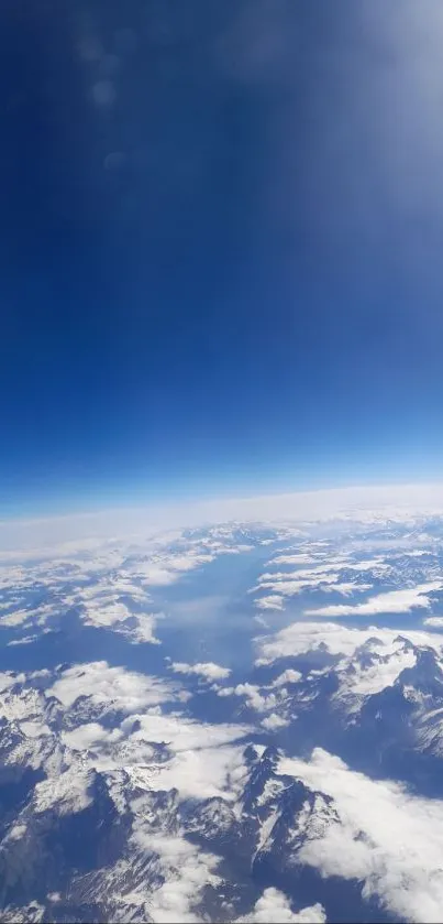 A stunning view of snow-capped mountains beneath a vivid blue sky from above.