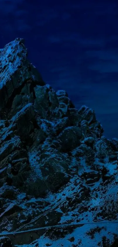 Snowy mountain under dark blue night sky.