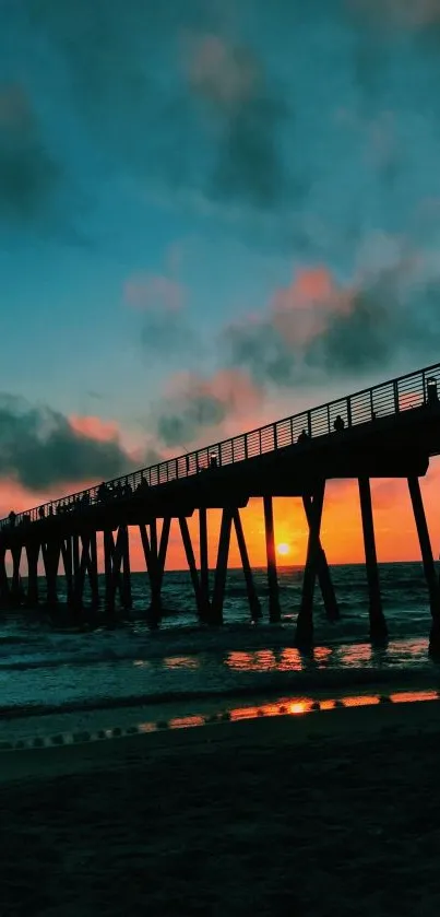 Silhouette of a pier at sunset over ocean waves.