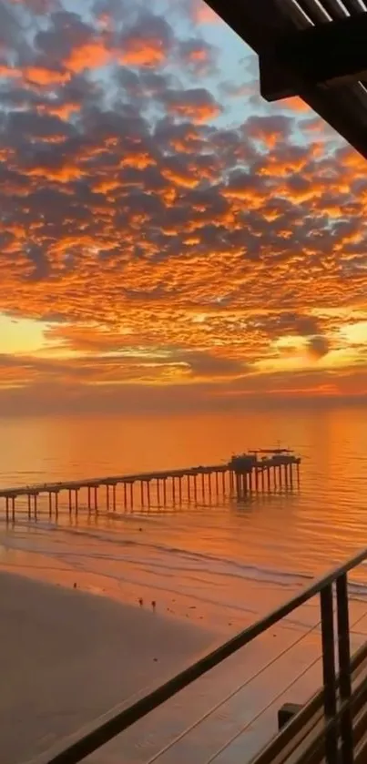 Beautiful sunset over a tranquil beach with an orange sky and pier silhouette.