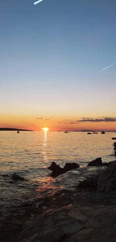 Vibrant sunset over a rocky beach, with a serene ocean view.