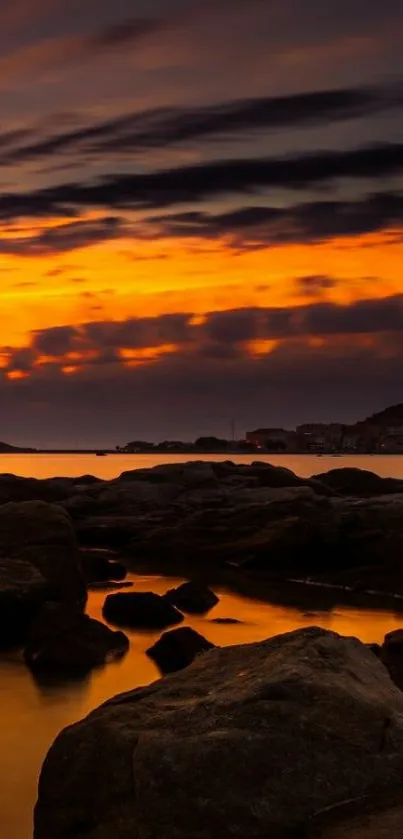 Vibrant sunset over a rocky beach under an orange sky.