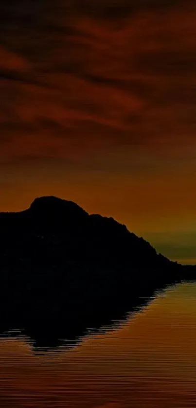 Sunset over mountains with reflection on tranquil water.