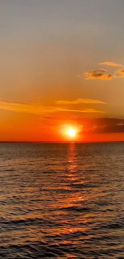 Vibrant sunset over a calm ocean reflecting orange hues.