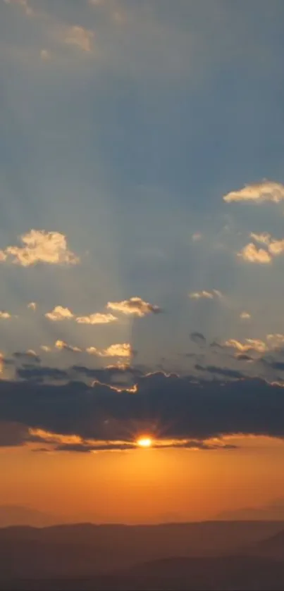 Serene sunset over mountains with dramatic clouds and golden sky.