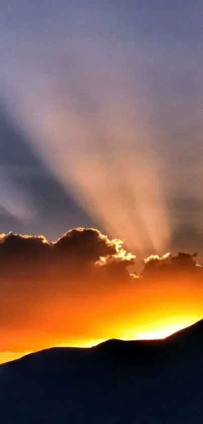 Majestic sunset with rays over silhouette mountains.