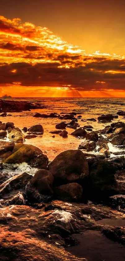 Serene sunset over rocky ocean shore with vibrant amber hues.