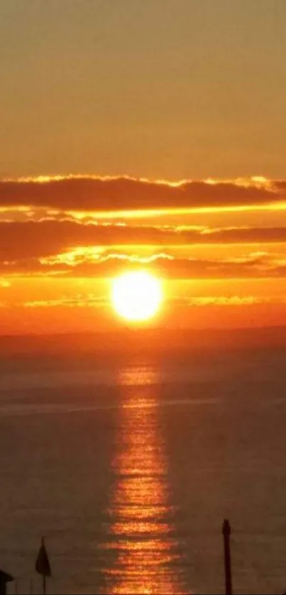 A vibrant sunset over the ocean with orange hues and silhouetted skyline.