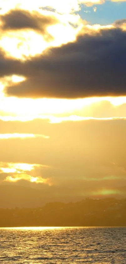 Golden sunset over water with cloudy sky.