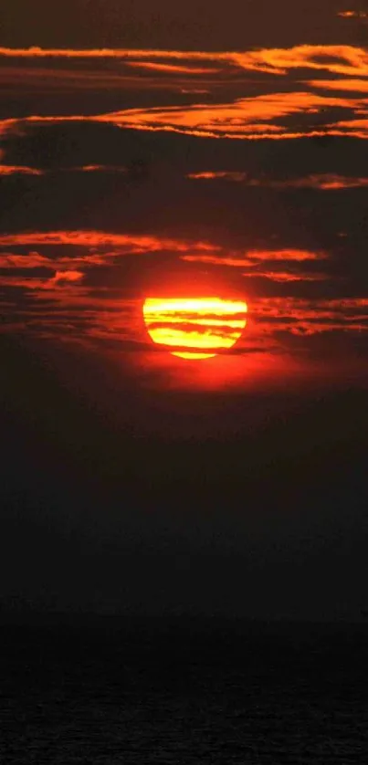 Vibrant orange sunset over dark ocean horizon.