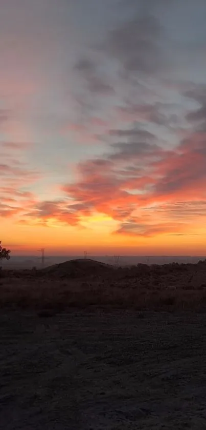 Vibrant sunset sky with orange and pink hues over a serene landscape.