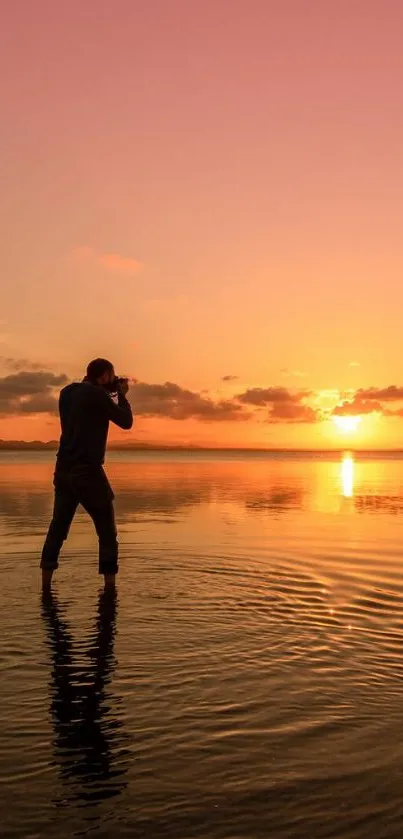 Silhouette photographer captures sunset reflection on calm waters.