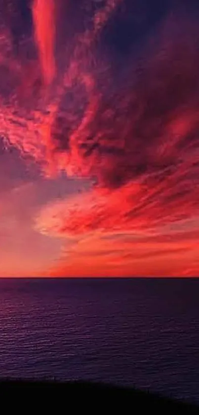 Stunning sunset over ocean with vibrant red sky clouds.