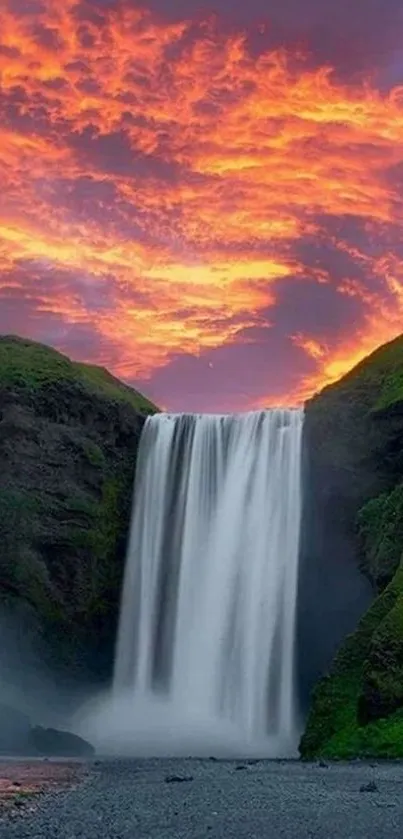 Waterfall tumbles under vibrant orange sunset sky.