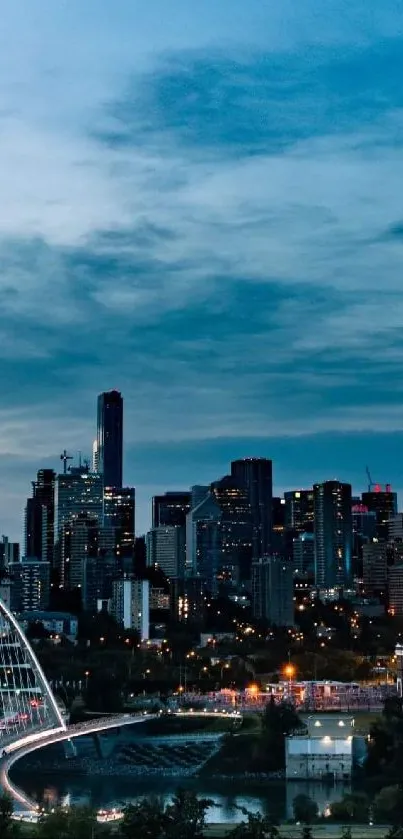 City skyline with bridge at dusk, lights glowing under a dark blue sky.