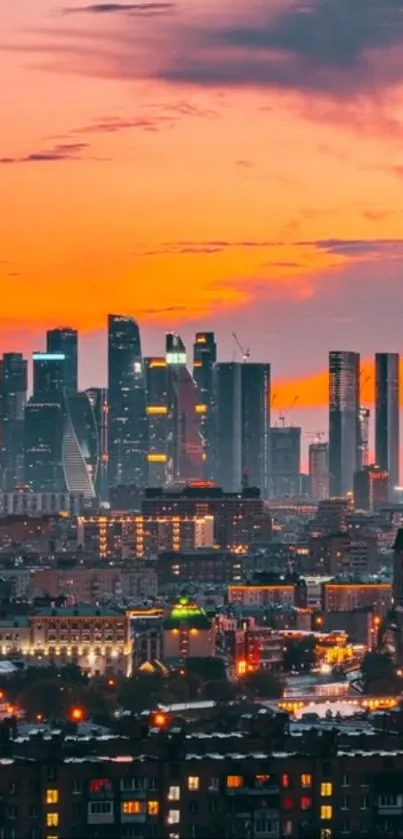 Skyline at sunset with illuminated buildings in a vibrant orange sky.