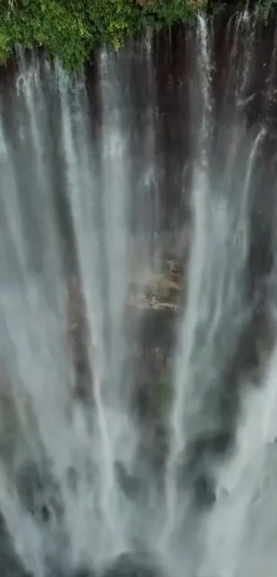 Aerial view of a majestic waterfall cascading down lush greenery.