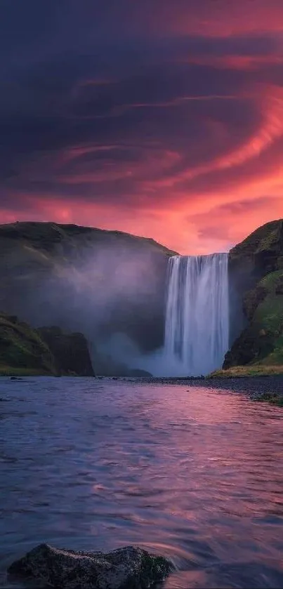 Waterfall at sunset with vivid pink sky, lush green hills, and serene waters.