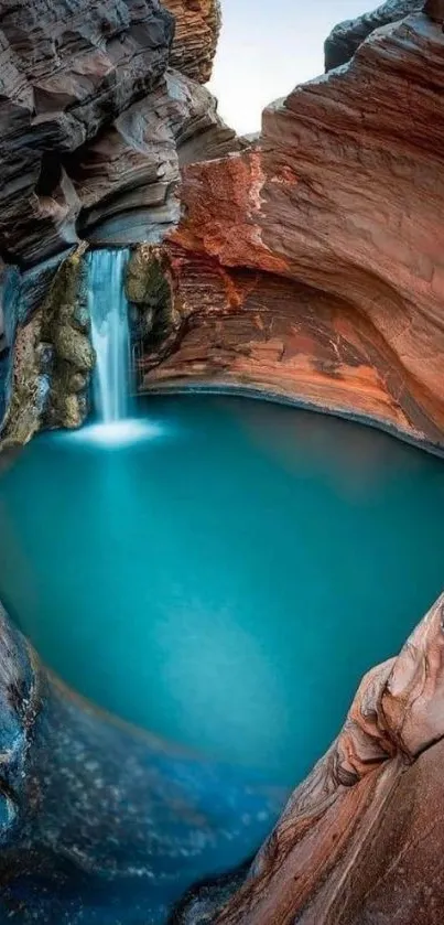 Stunning waterfall flowing into turquoise canyon pool with rocky backdrop.