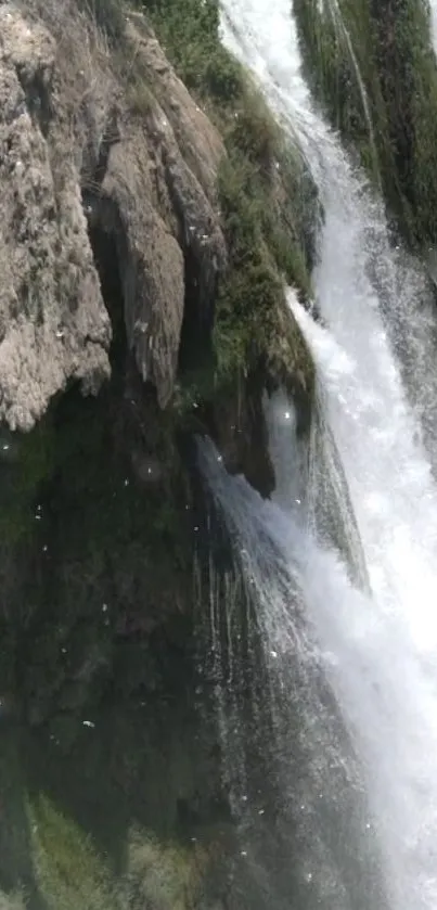 Waterfall cascading over rugged rocks with lush greenery.