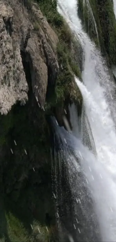 Waterfall cascading down a rocky cliff with lush greenery.