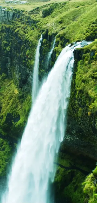 Waterfall cascading down a lush green cliffside, perfect nature wallpaper.