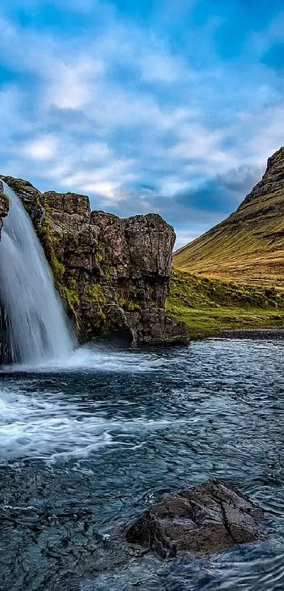 Waterfall and mountain landscape under a clear blue sky.