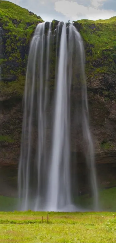 Waterfall cascading down green cliffs with lush surroundings.