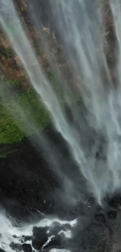 A breathtaking waterfall cascading over green rocks.